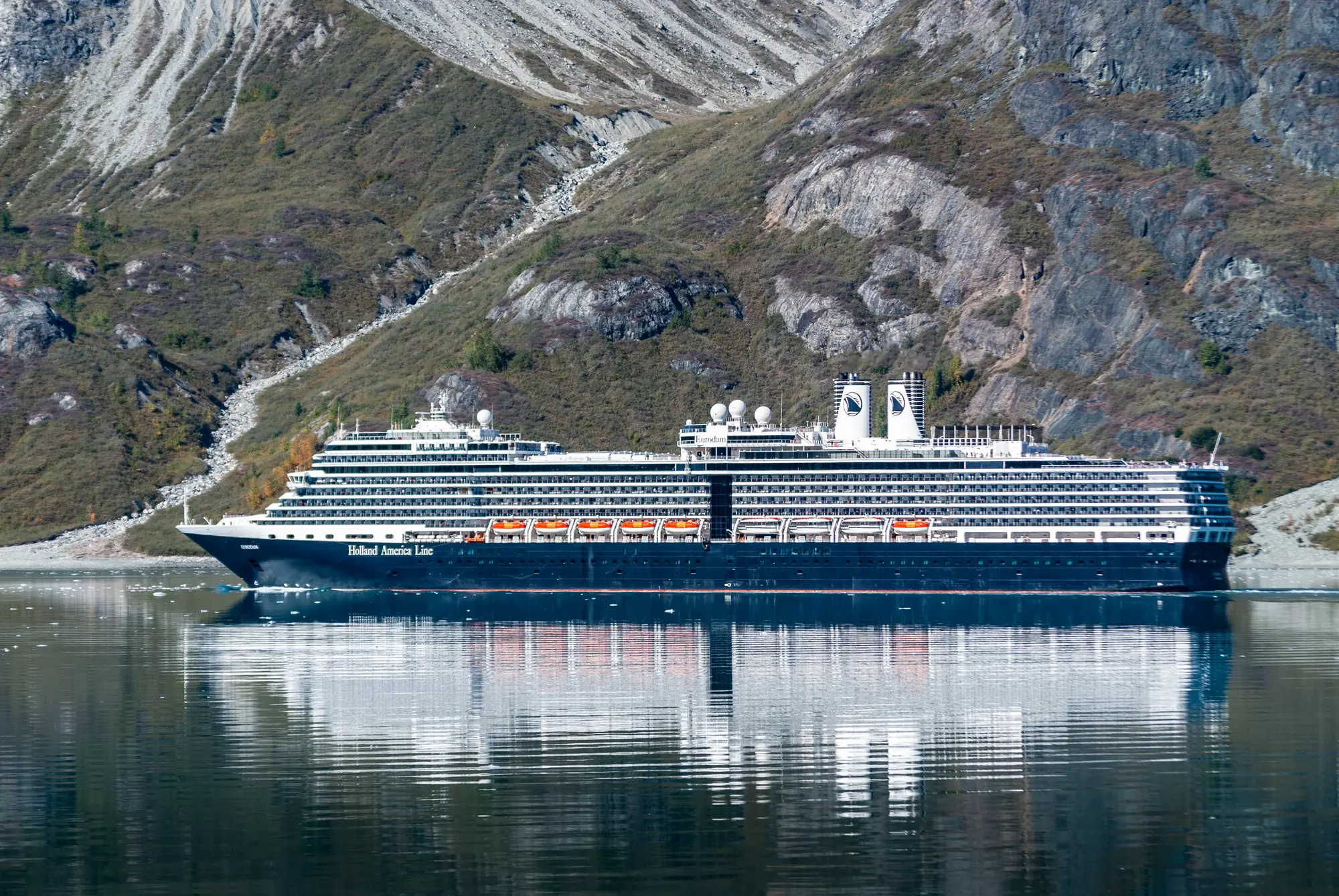 A cruise ship on still water below the mountains of Glacier Bay, Alaska